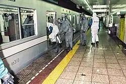 GSDF personnel (with olive-drab colored clothing) and TMPD officers (with white clothing) entering contaminated vehicles.