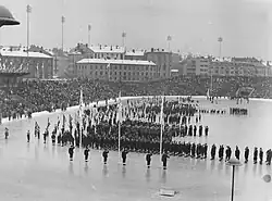 Long-shot of Olympic stadium with many athletes standing in neat formation behind their national flags