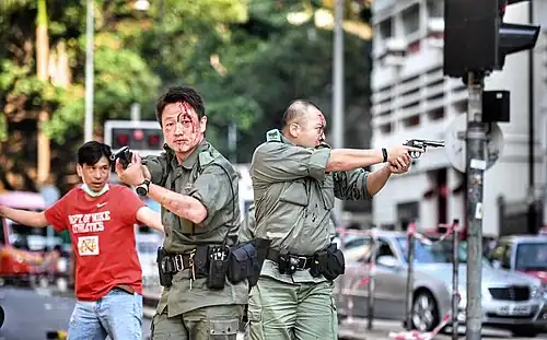 Two police officers firing warning shots to the sky then pointing to protesters in Yau Ma Tei