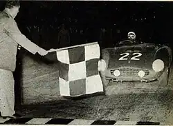 The race director Renzo Castagneto flies the chess flag to the winner Phil Hill on Ferrari.