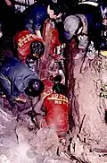 Rescue workers wearing orange uniforms can be seen crouching.