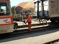 Meter gauge TPF BDe 4/4 123 is coupled to a standard gauge wagon on transporter trucks in Broc-Fabrique