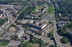 Aerial view of Kloten Balsberg station (to the left, in 2011) from the south; the railway platform crosses the bridge over the road, whilst the tram platforms are to the left and linked by footbridge