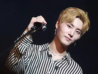 An image of Young K looking into the camera while holding a microphone