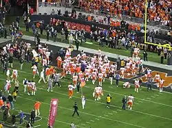 Clemson players celebrate in the end zone near the majority of their fans.