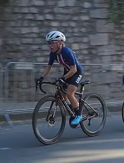 Woman riding a road bicycle, wearing a red, white, and blue cycling jersey which reads "USA"