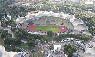 Photo with aerial view of the stadium with red athletics tracks around green grass