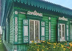 A green wooden house with elaborately carved elements