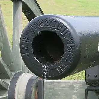 Closeup photo shows markings on the muzzle of a black cannon.