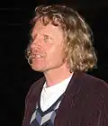 Grayson Perry, a man wearing a corduroy jacket who is looking to his right