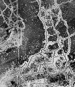An aerial reconnaissance photograph of the opposing trenches and no man's land between Loos and Hulluch in Artois, France. German trenches are at the right and bottom, and British trenches are at the top left. The vertical line to the left of centre indicates the course of a pre-war road or track.