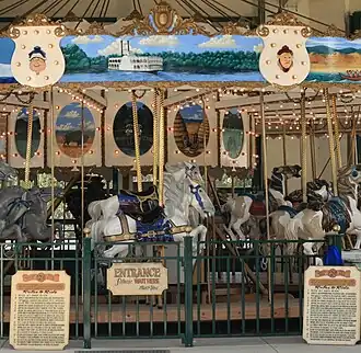 A historic carousel adorned with paintings and surrounded by a metal fence