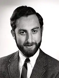 Black and white photo of a bearded man wearing a suit and a tie