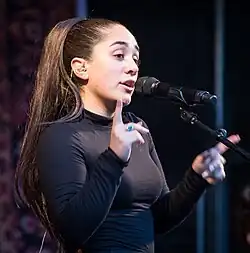 Delara singing into a microphone.