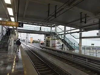 Multiple people wait at the platforms of a station.