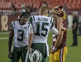 A photo of three players chatting on a football field