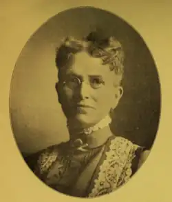 B&W oval portrait photo of a woman with her hair in an up-do.