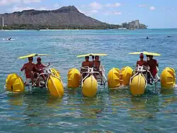 Human powered aqua-cycle water trikes in the Pacific Ocean with Diamond Head, Hawaii in the background.