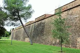 Large curtain wall with embrasures and bartizan in the background