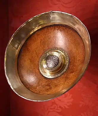 The "Robert Chalker Mazer", Britain 1480–1500, Victoria and Albert Museum. Maplewood with silver-gilt rim and boss. The boss is engraved with the Trinity, originally enamelled, an unidentified merchant's mark and the inscription ROBERT CHALKER IESUS.