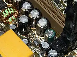 Failed Choyo capacitors (black color) which have leaked brownish electrolyte onto the motherboard