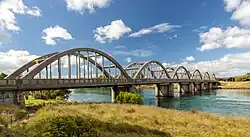 A grey bridge spanning a river with many semicircular arcs