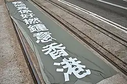 Someone spread out a large straight flag on the tramway off CNT Center in Wan Chai, saying "We really love Hong Kong."