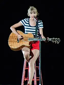 Taylor Swift on the Red Tour, playing an acoustic guitar