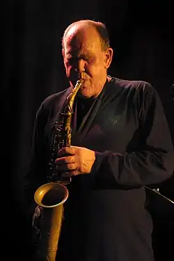 A man playing alto saxophone in the low light of a jazz club