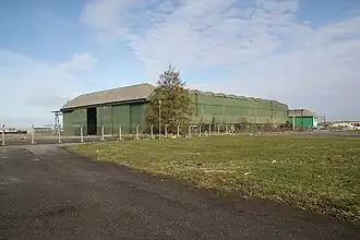 A large green, steel clad hangar