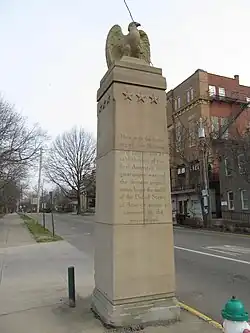 view up at an Eagle sculpted in stone on top of a square monolith with an inscription about Marietta's establishment