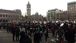 Crowd of people in Copley Square, Boston. Many are holding signs.