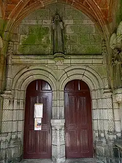 The double doored entrance to the church and the statue of Jesus giving a blessing whilst holding a globe