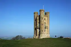 Golden limestone tower with three circular turrets that run the height of the building.