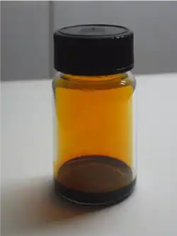Glass vial containing dark brown liquid and vapor