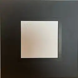 A thick black border around a peach square with a foil stamp