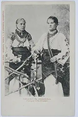 Two women, the one on the right holding a traditional bag