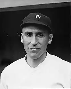 A man smiles while wearing a white baseball jersey with a dark cap with a white "W" on the center.