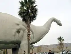 Exterior view of large concrete Brontosaurus sculpture with entrance visible in its belly