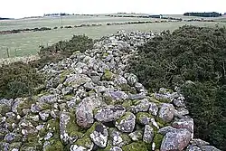Many granite stones over a long, rectangular area, in a green landscape.