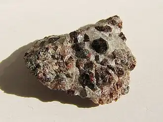 Dark red hexoctahedral crystals on light colored rock