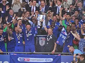 A football team celebrating with a trophy.