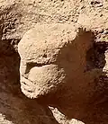 Carved head in structure AB (on site)