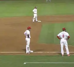 Runners on second and third base, with the third-base coach nearby