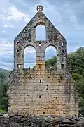 Façade of a ruined building, with the Knights Templar cross at the top.