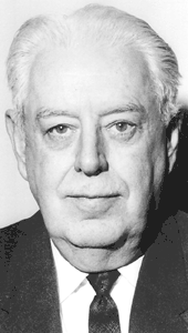 Black and white of a late-middle-aged man with white hair, wearing a dark suit jacket, dark necktie, and white dress shirt