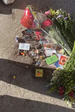 The hole on February 18, surrounded by gifts from visitors including flowers, coins, glasses, and Pokémon cards
