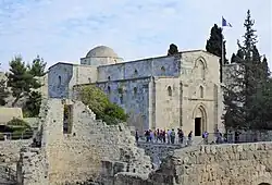 A stone church behind stone ruins of an older building