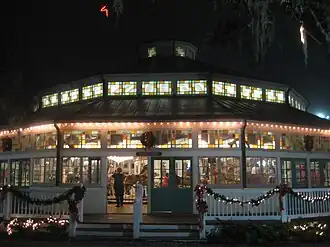 A shelter building at nighttime with stained-glass windows containing a historic carousel