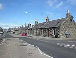 Facing down two lane street with a row of bungalows on the right